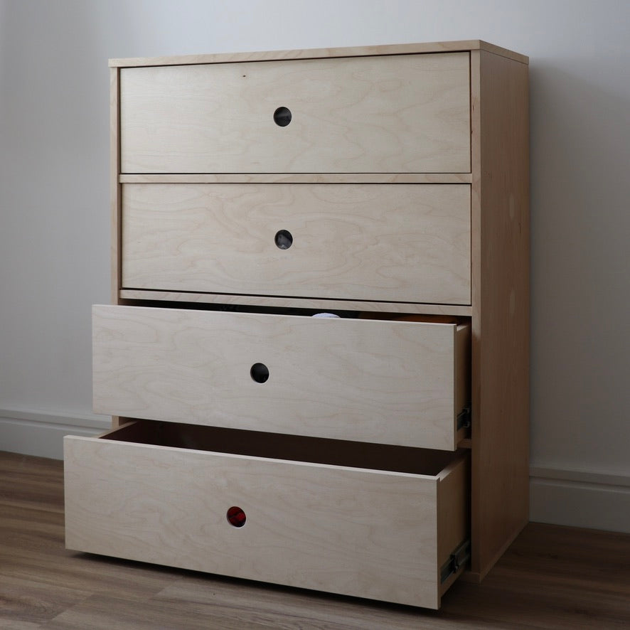Wooden dresser with four drawers against a plain wall.